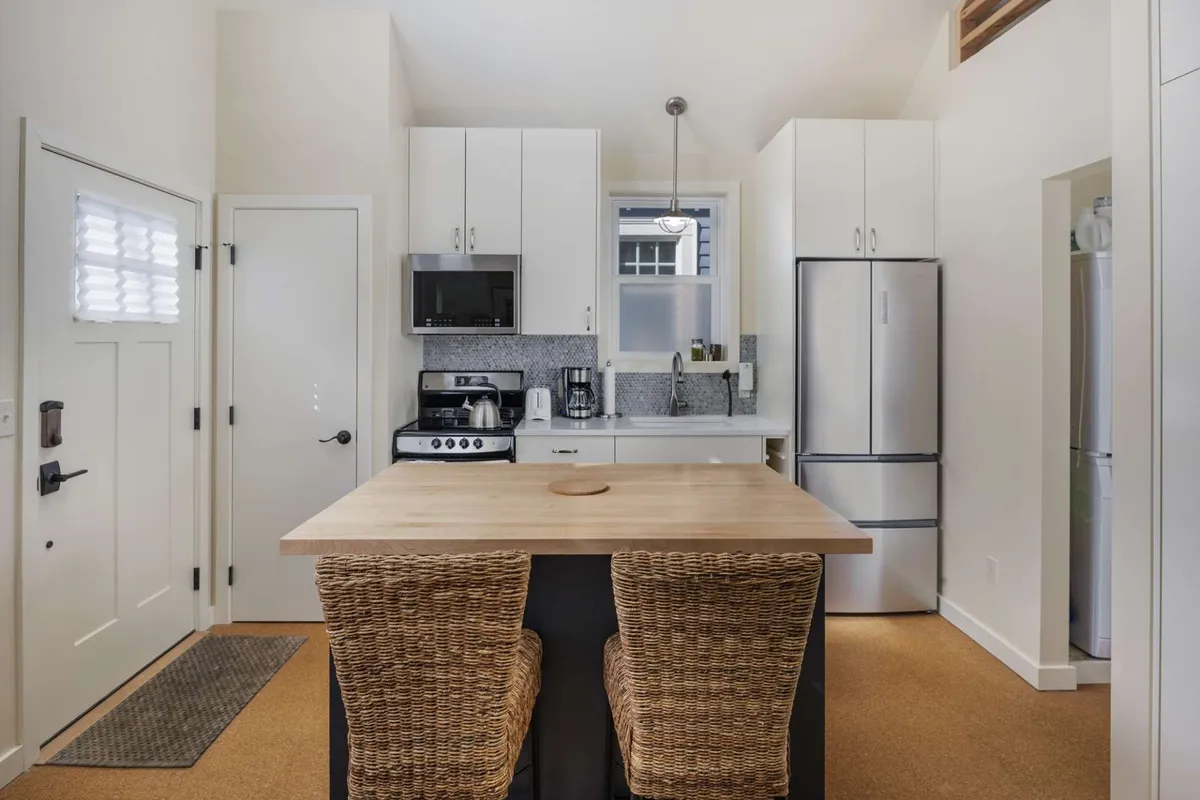 This photo focuses on the kitchen, showcasing stainless steel appliances, a roomy breakfast bar, and sleek cabinetry. Natural light brightens the workspace, emphasizing the kitchen's modern appeal and suitability for both daily meals and creative cooking.